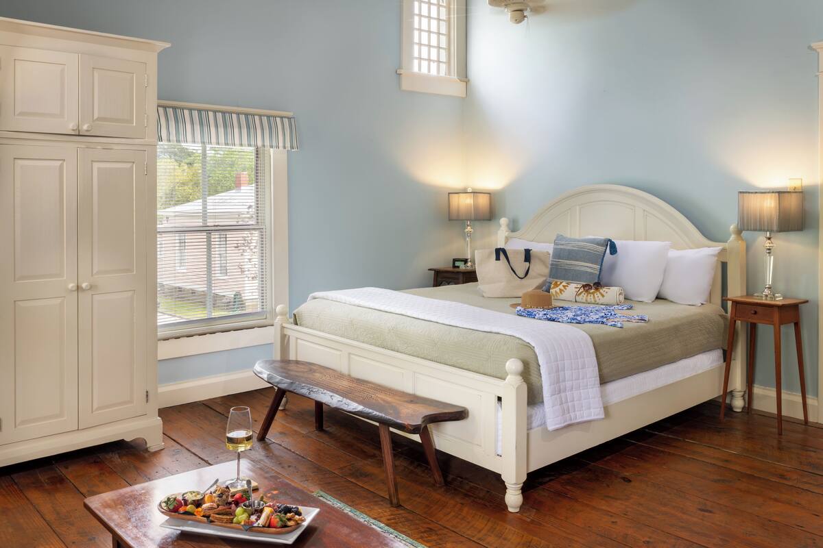 Quarto com cama, mesas de cabeceira, um banco e bandeja de café da manhã.