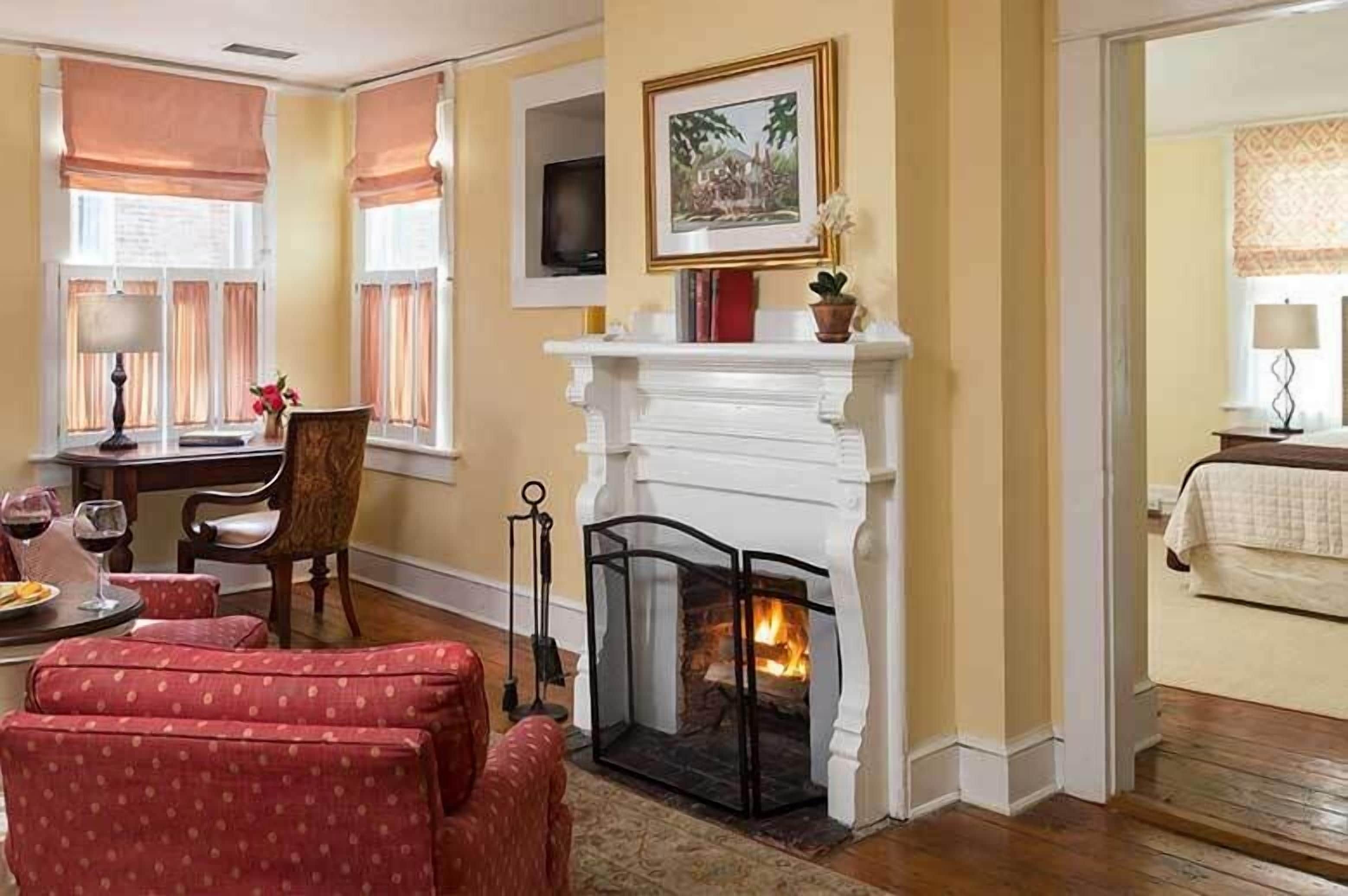A cozy room with a fireplace, a dining area with a table and chairs, and a bed with a nightstand.