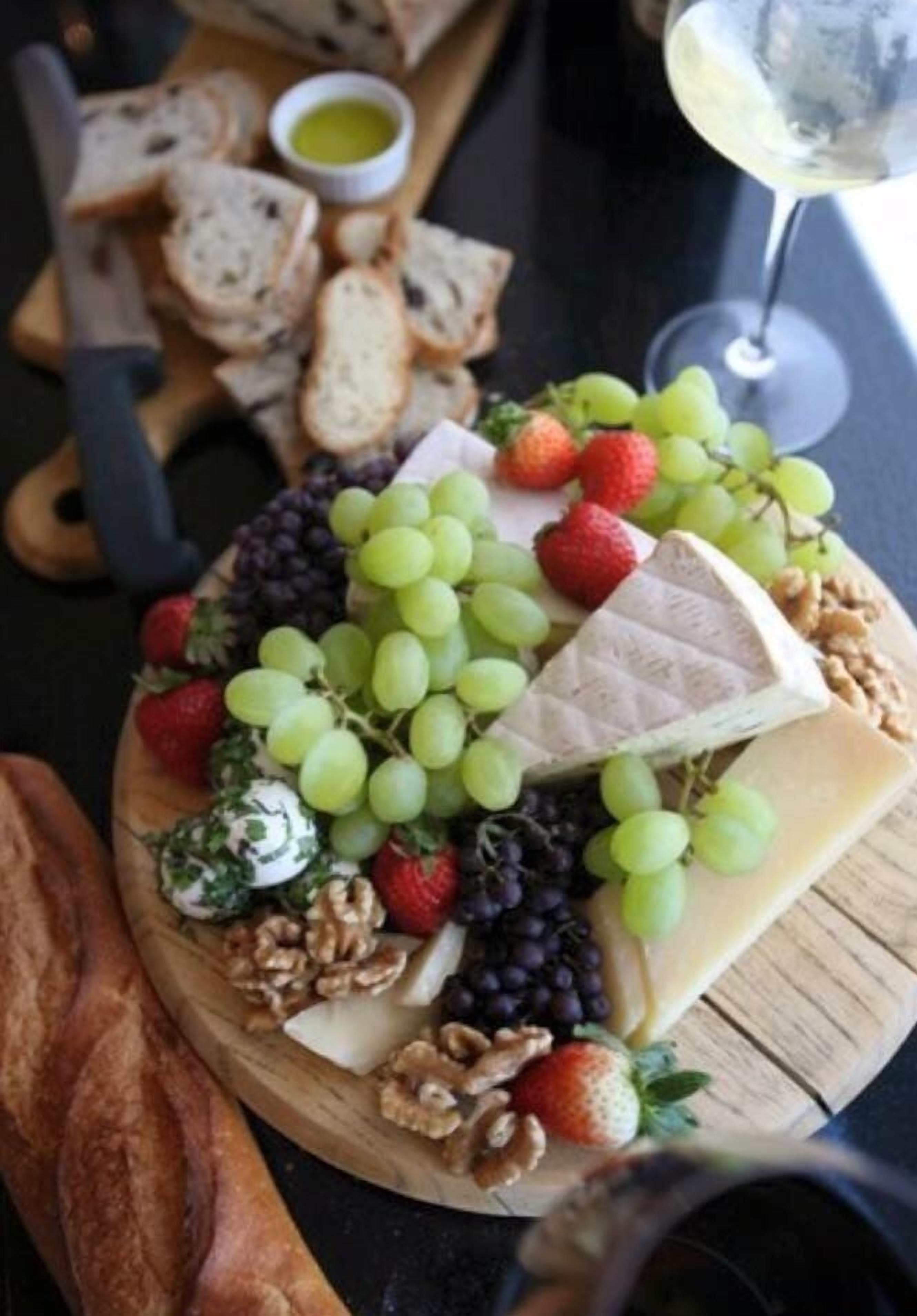 A charcuterie board with various cheeses, fruits, and nuts.