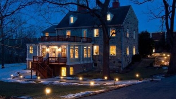 A stone house with a porch and multiple windows, surrounded by trees and a snow-covered yard. - The Wayside Inn Bed & Breakfast (Ellicott City)