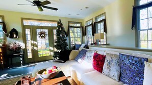 A spacious living room with a white sofa, a Christmas tree, and large windows. - The Wayside Inn Bed & Breakfast (Ellicott City)