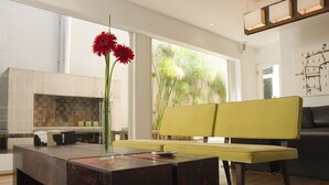 A modern living room with a large window, a yellow sofa, a wooden coffee table, and a fireplace. - Didi Rooms (Buenos Aires)