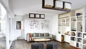 A modern living room with a sofa, ottomans, a coffee table, and a bookshelf. - Didi Rooms (Buenos Aires)