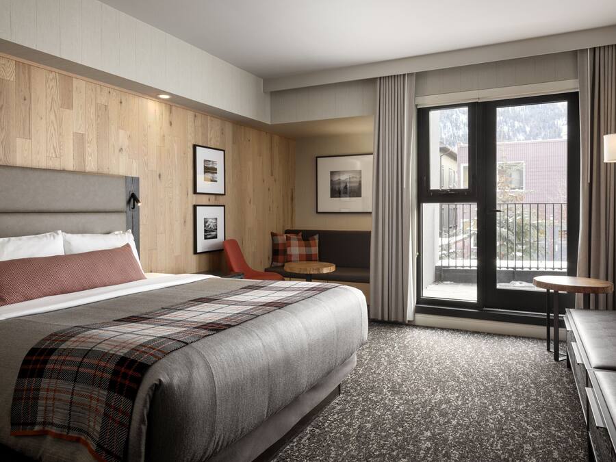 Habitació d'hotel amb un llit gran, un sofà, una taula petita i una finestra amb vistes.