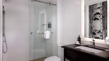 Un bagno moderno con box doccia in vetro, un water bianco, un lavello in granito scuro e uno specchio grande.