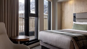 A modern bedroom with a large bed, a chair, and a small table. - Peaks Hotel & Suites (Banff)