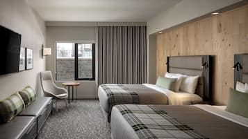 A hotel room with two beds, a sofa, a TV, and a small table.