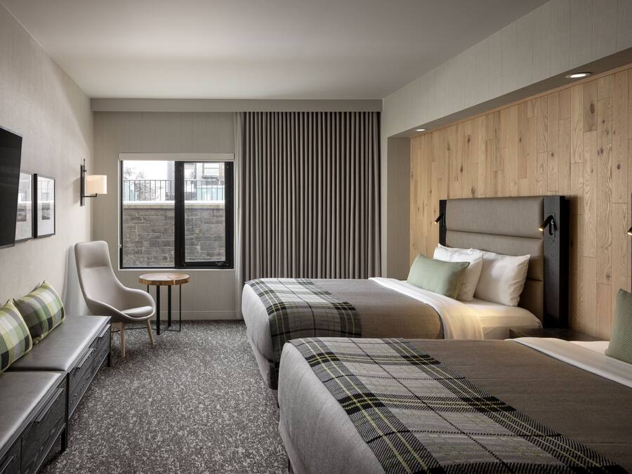 A hotel room with two beds, a sofa, a TV, and a small table.