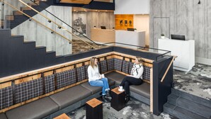 A modern interior with a central staircase, seating area, and a reception desk. - Peaks Hotel & Suites (Banff)