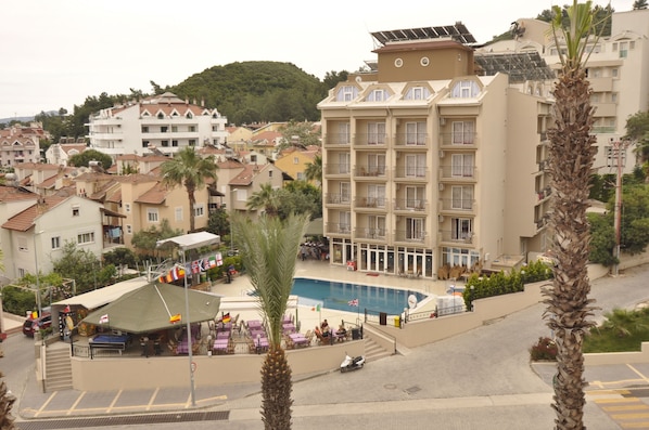 Um hotel com piscina, várias varandas e vista para o bairro ao redor.