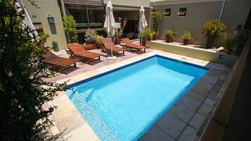 Een buitenzwembad, ligstoelen bij het zwembad