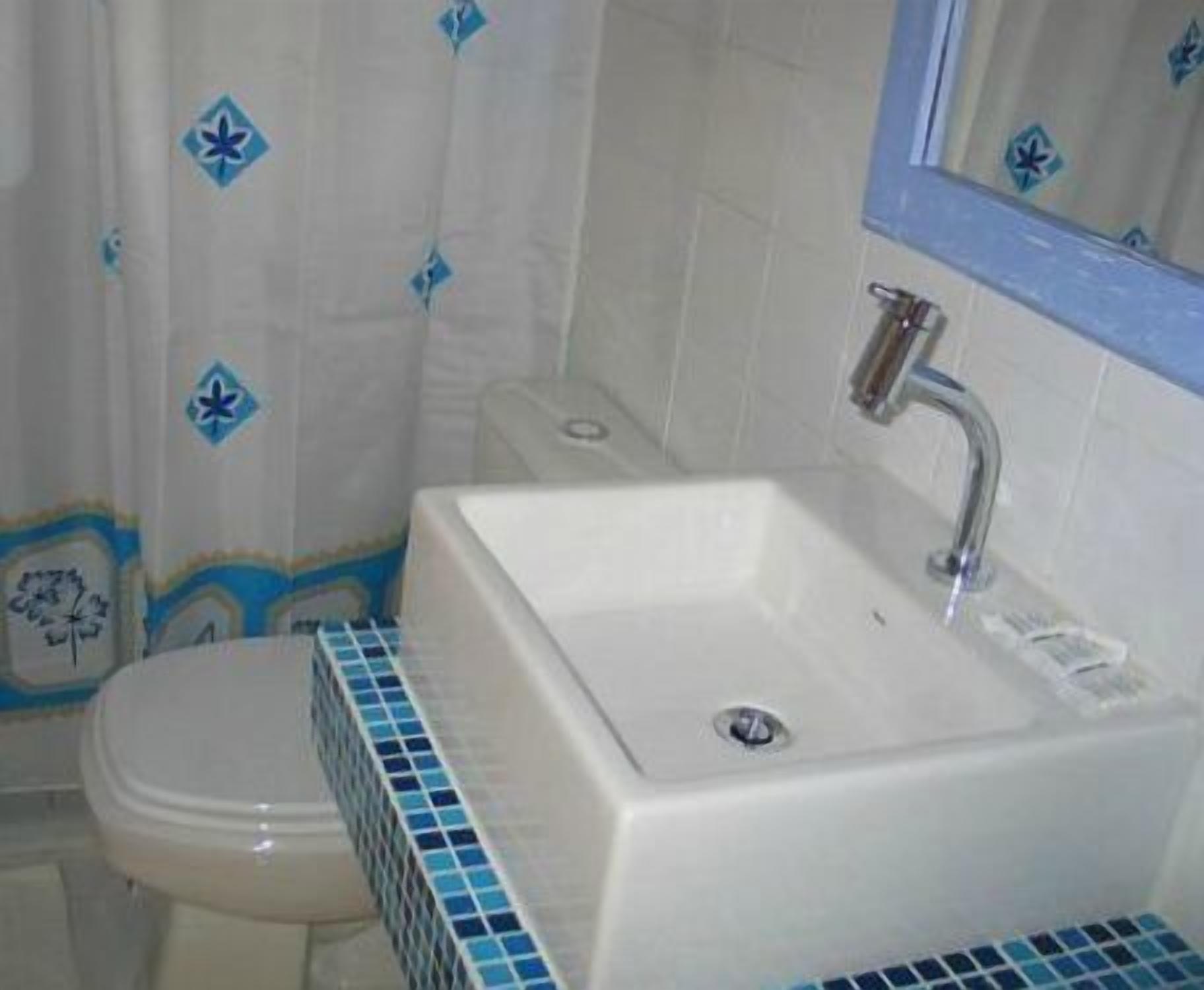 A bathroom with a white sink, a mirror above it, and a toilet.