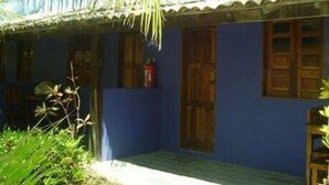 Un bâtiment à l’extérieur bleu et au toit recouvert de tuiles, doté de portes et de fenêtres en bois.