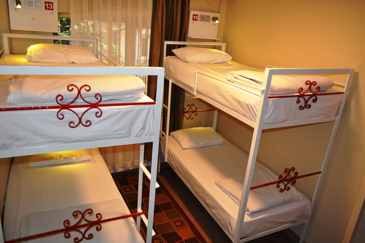 Bunk beds in a room with a window, a bedside table, and a wall clock.