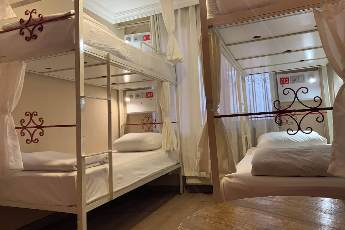 A room with bunk beds, a wooden table, and a curtain.