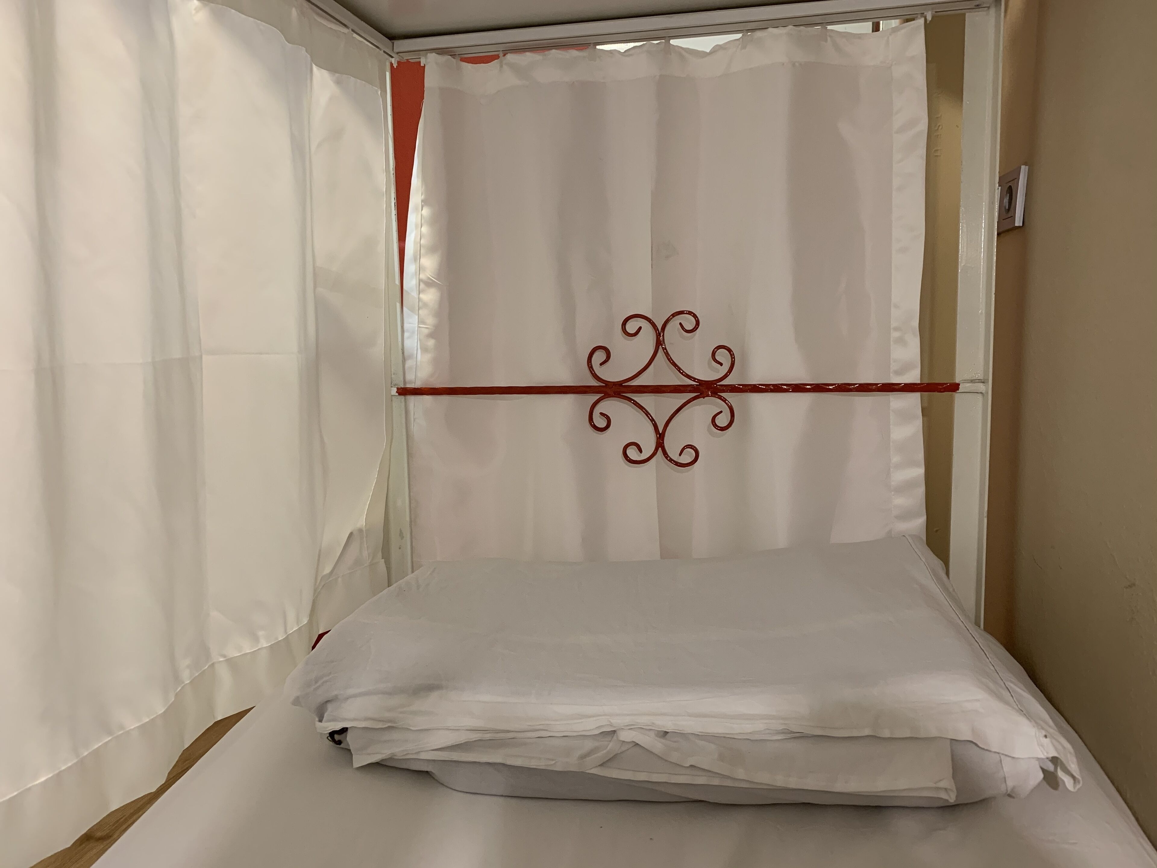 Une chambre avec un lit, des rideaux blancs et une tige décorative en métal.
