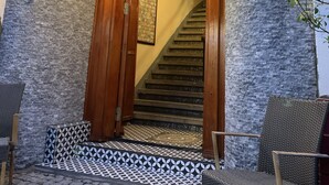 A wooden staircase leading to a room with a patterned floor and a chair in the foreground. - Antique Hostel & Guesthouse (Istanbul)