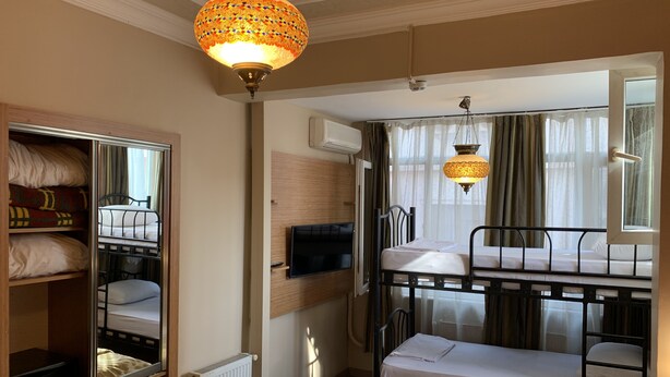 Una habitación de hotel con literas, un armario, un televisor y un radiador.