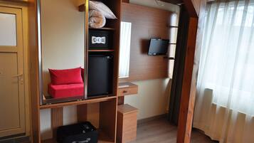 A compact room with a wardrobe, a small desk, a television, and a suitcase.