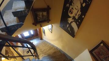 Eine Wendeltreppe mit Geländer, ein Frauenbild an der Wand und ein gerahmtes Bild darüber.