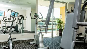 Un gimnasio con equipo de ejercicio, un espejo grande y vistas al exterior.