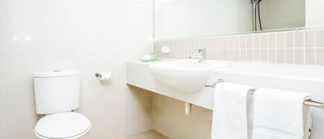 Un baño moderno con inodoro, lavamanos y ducha.