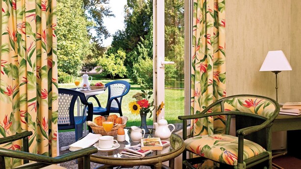 Una mesa con sillas dispuesta para el desayuno, con vistas a un jardín.