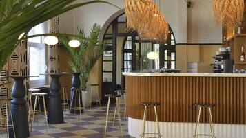 A bar area with a checkered floor, bar stools, and hanging wicker lamps.