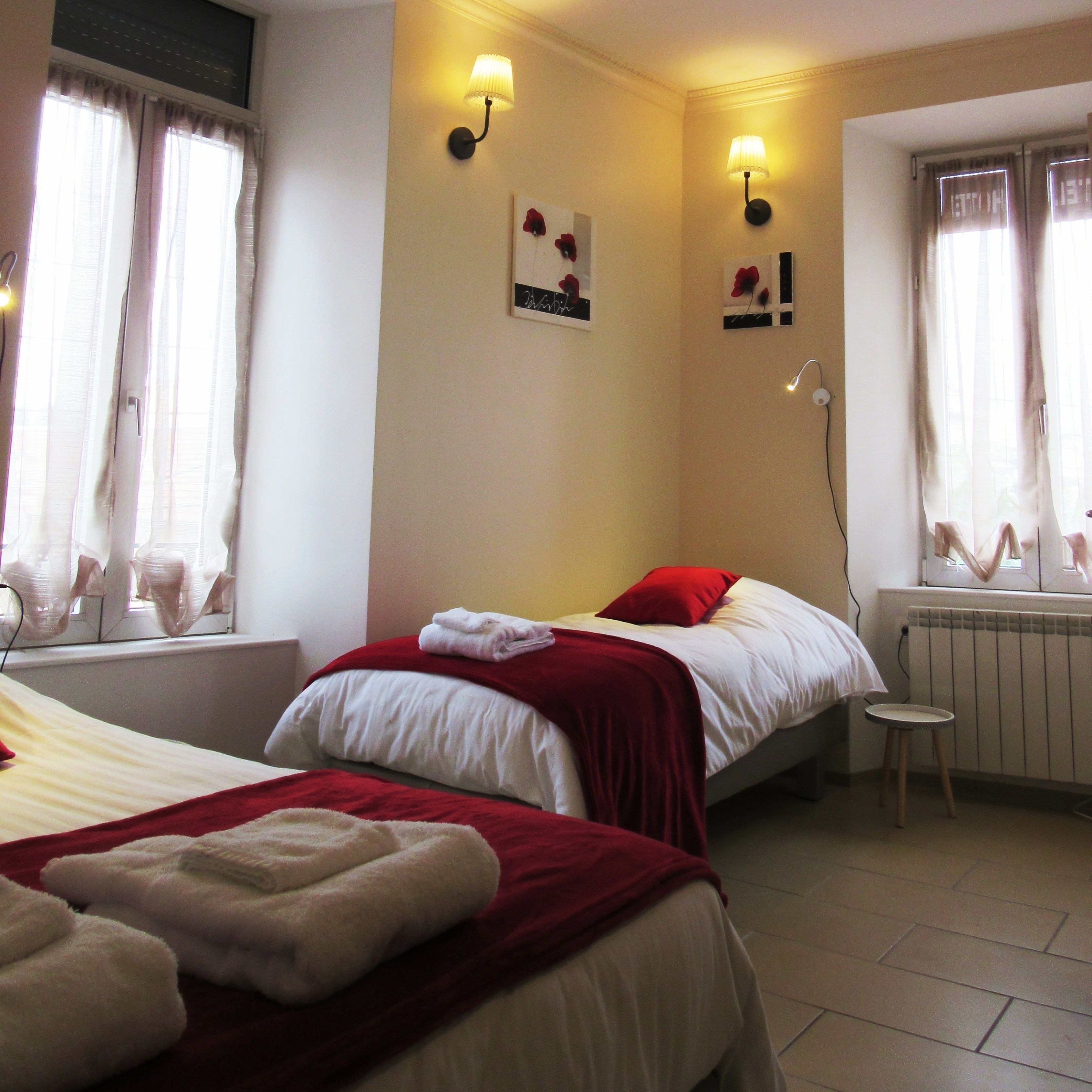 Una habitación de hotel con dos camas, un taburete pequeño y un radiador.