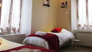 Una habitación de hotel con dos camas, un taburete pequeño y un radiador.