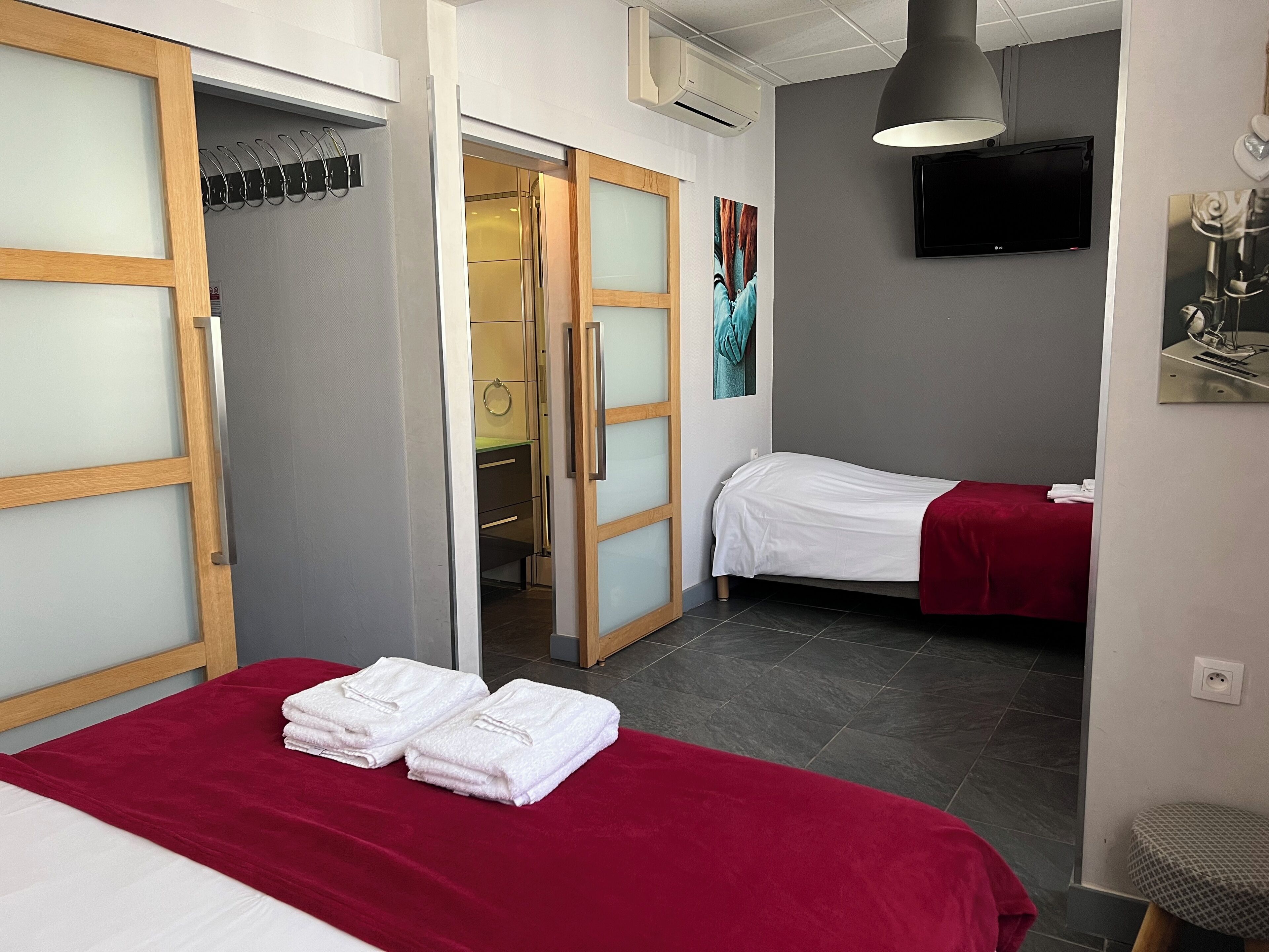 A hotel room with two beds, a TV, and a shower area.