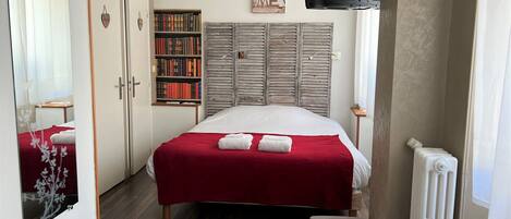 Una habitación de hotel con una cama, una estantería, un armario y un televisor montado en la pared.