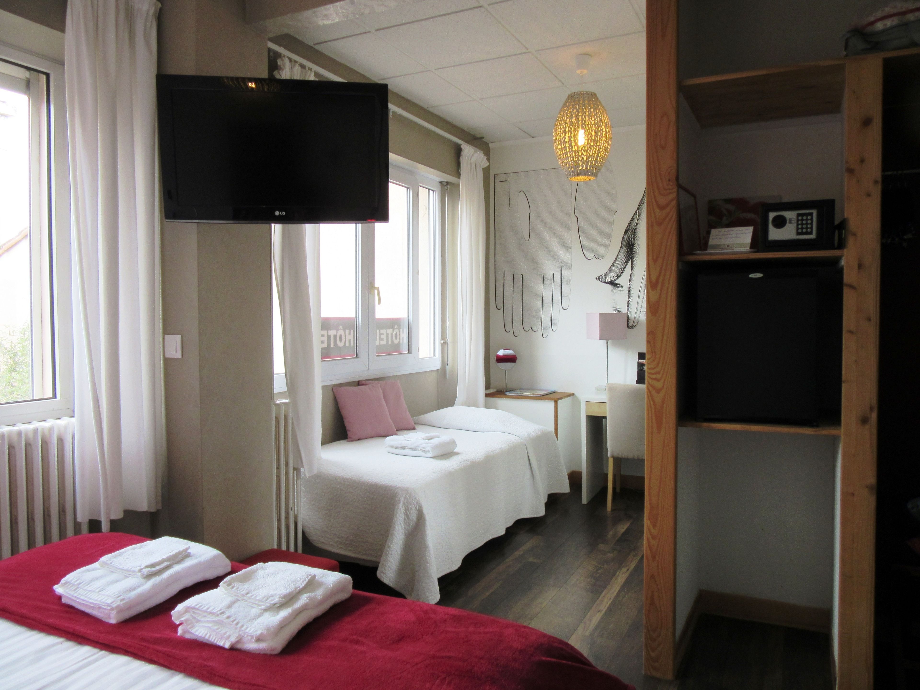 Een hotelkamer met een bed, een bureau, een televisie en een kledingkast.