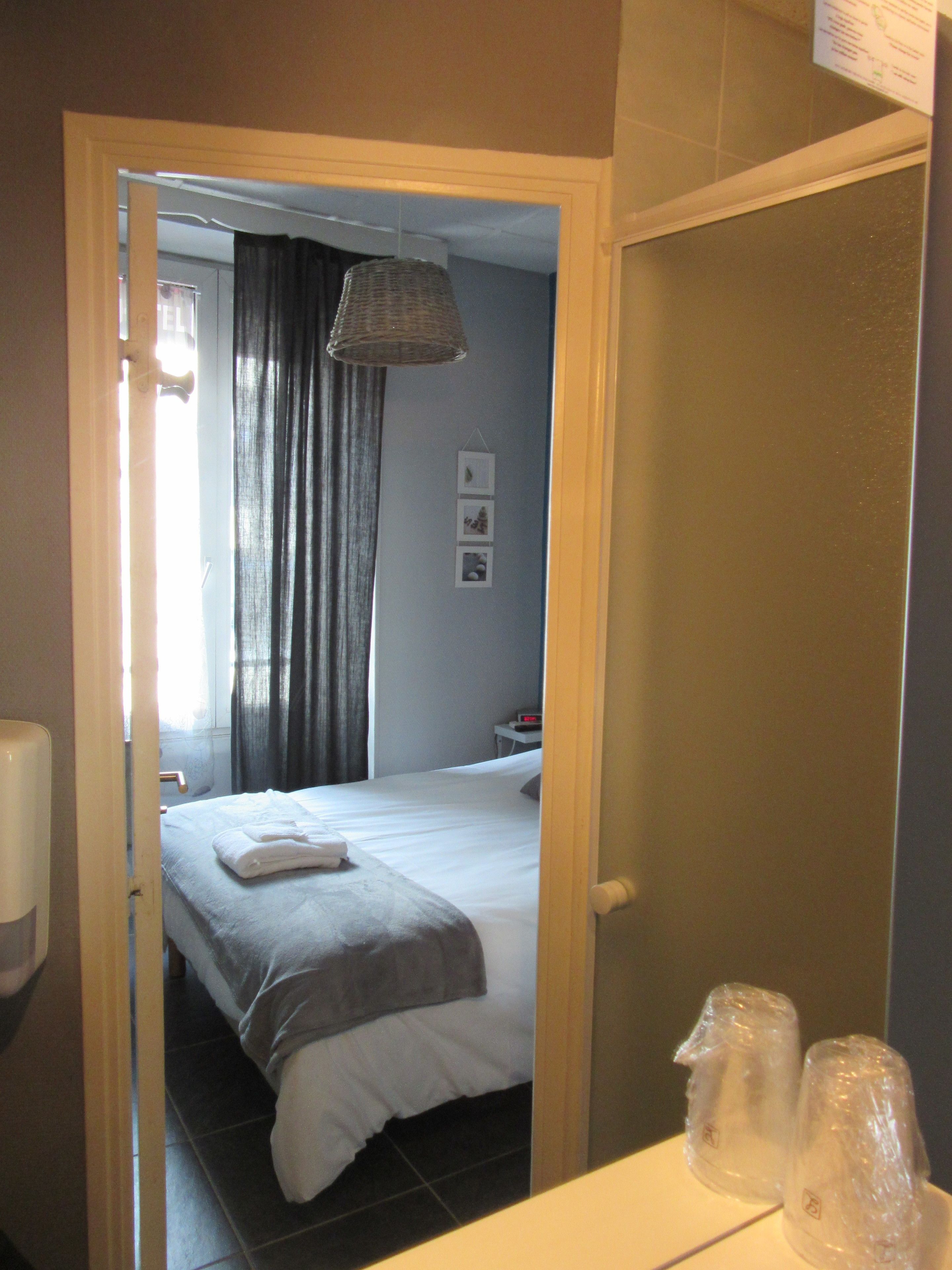 Quarto de hotel com cama, mesa de cabeceira, abajur e espelho.