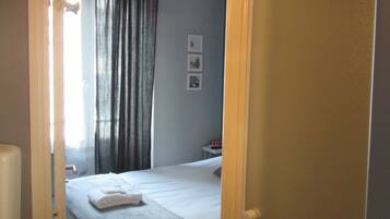 Quarto de hotel com cama, mesa de cabeceira, abajur e espelho.