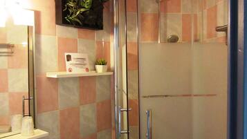 Un baño con cabina de ducha de vidrio, un lavabo blanco y un espejo sobre él.