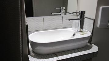 A modern bathroom with a white sink, chrome faucet, and a mirror above it.