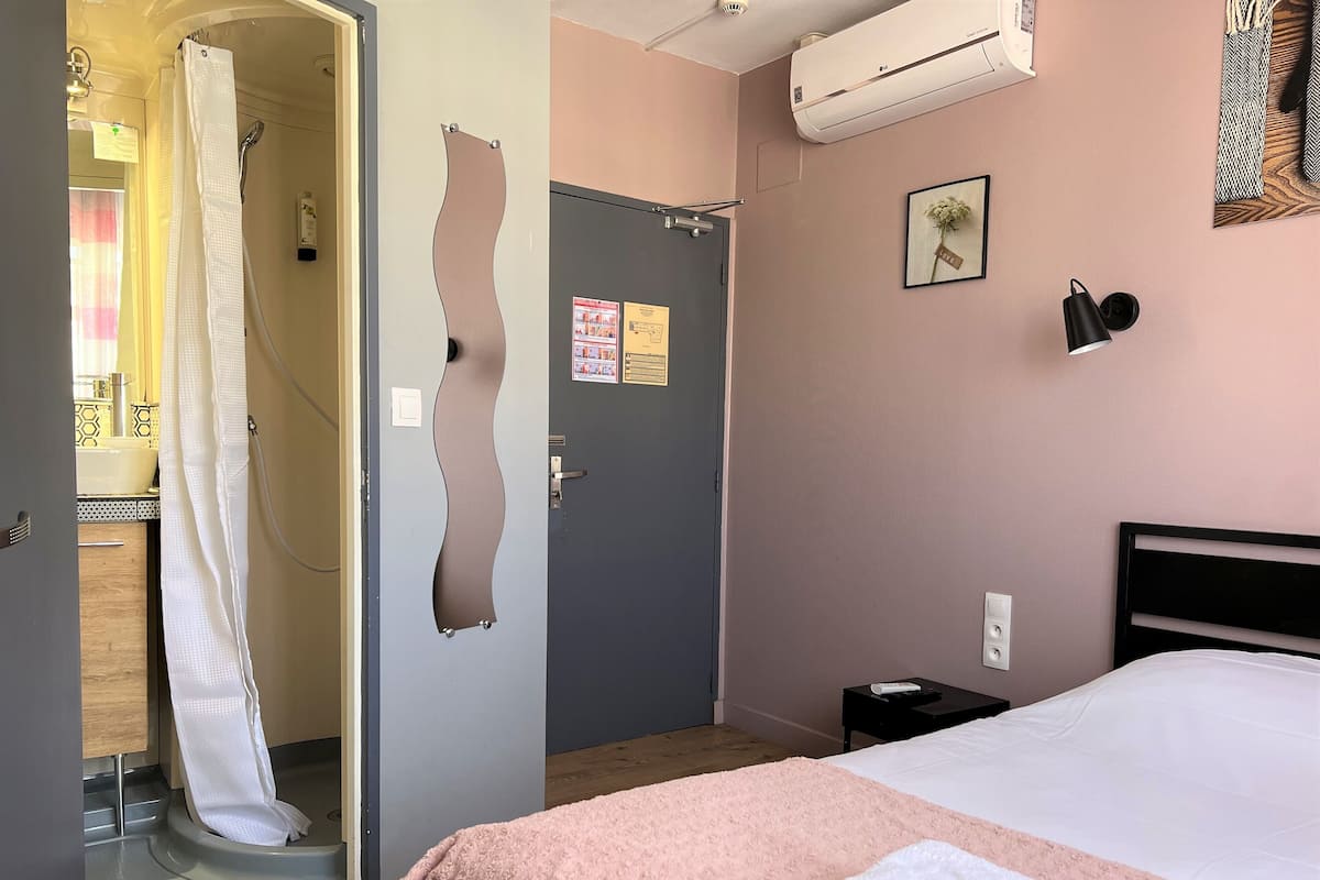 A hotel room with a bed, a bathroom with a shower, and a door with a unique design.