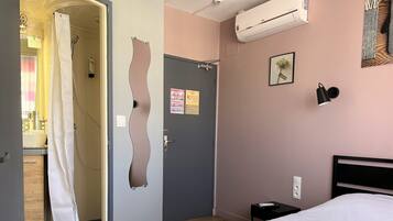 A hotel room with a bed, a bathroom with a shower, and a door with a unique design.
