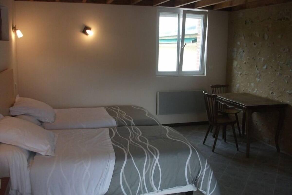 Ein Schlafzimmer mit Bett, Tisch und Stuhl. Ein Fenster bietet Blick auf den Strand.