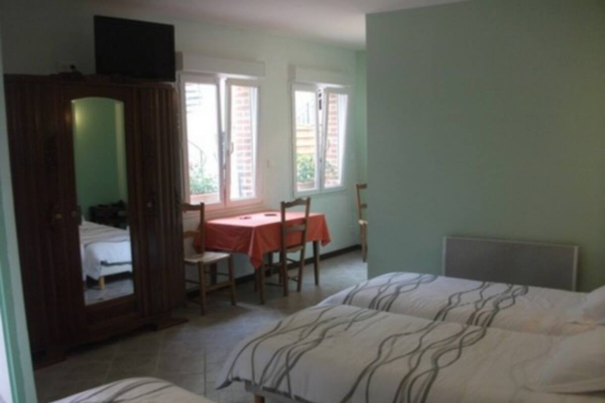 Ein Schlafzimmer mit zwei Betten, einem Holzschrank, einem Tisch mit Stühlen und einem Fenster.