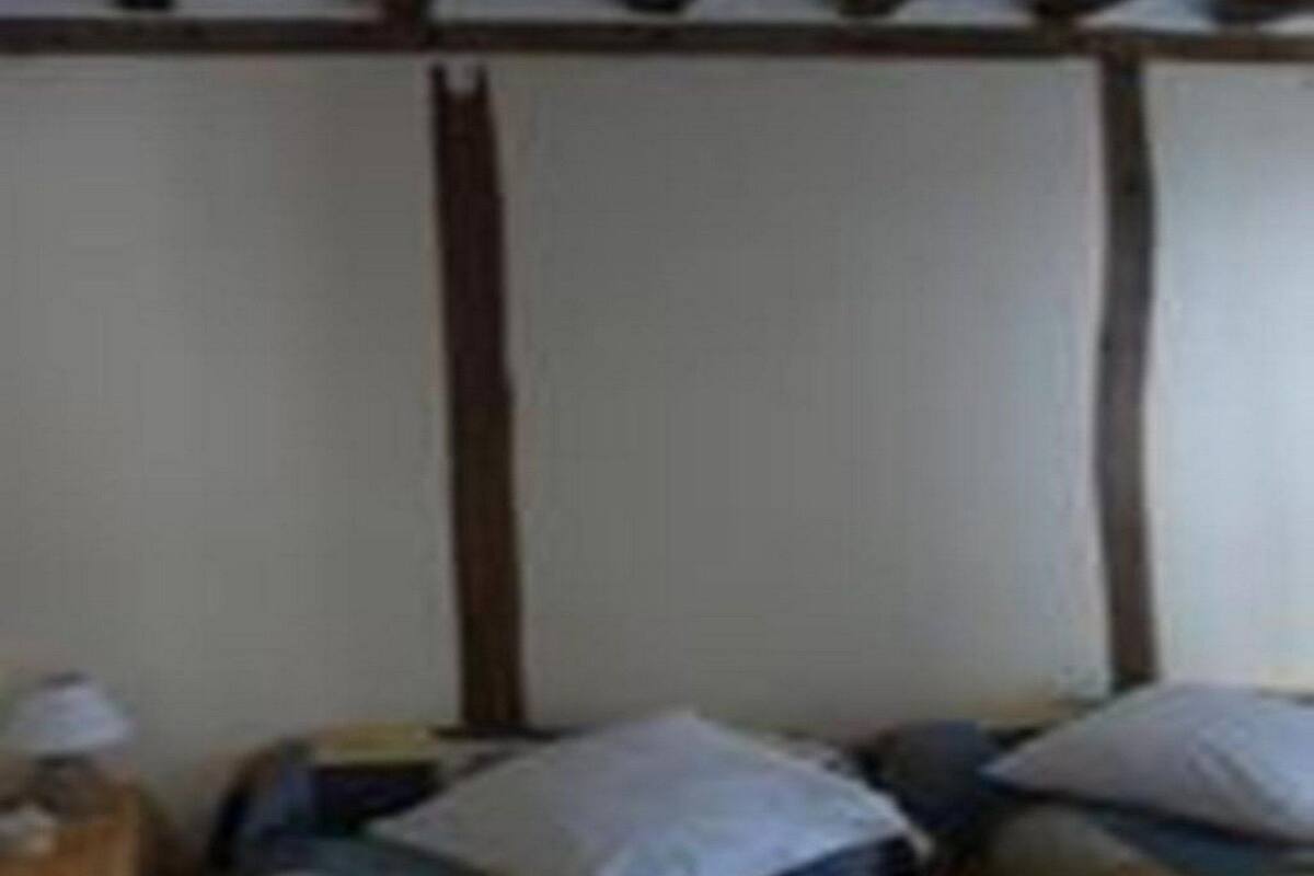 Ein Zimmer mit zwei Betten, Holzbalken an der Decke und einer schlichten Wand.