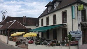 Un bâtiment doté d’une terrasse et d’une marquise verte, une enseigne indiquant « Logis » et un panneau signalant un parking situé à 200 mètres.