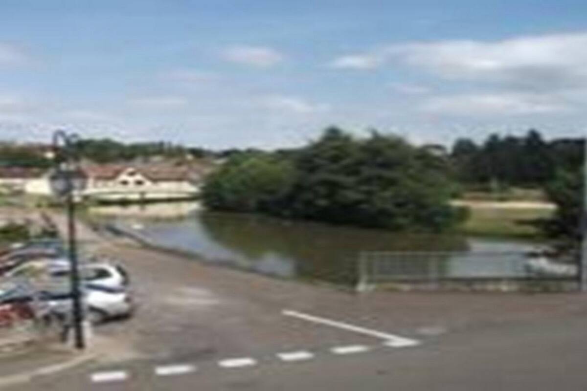 Blick auf einen Fluss mit geparkten Autos und einem Gebäude im Hintergrund.