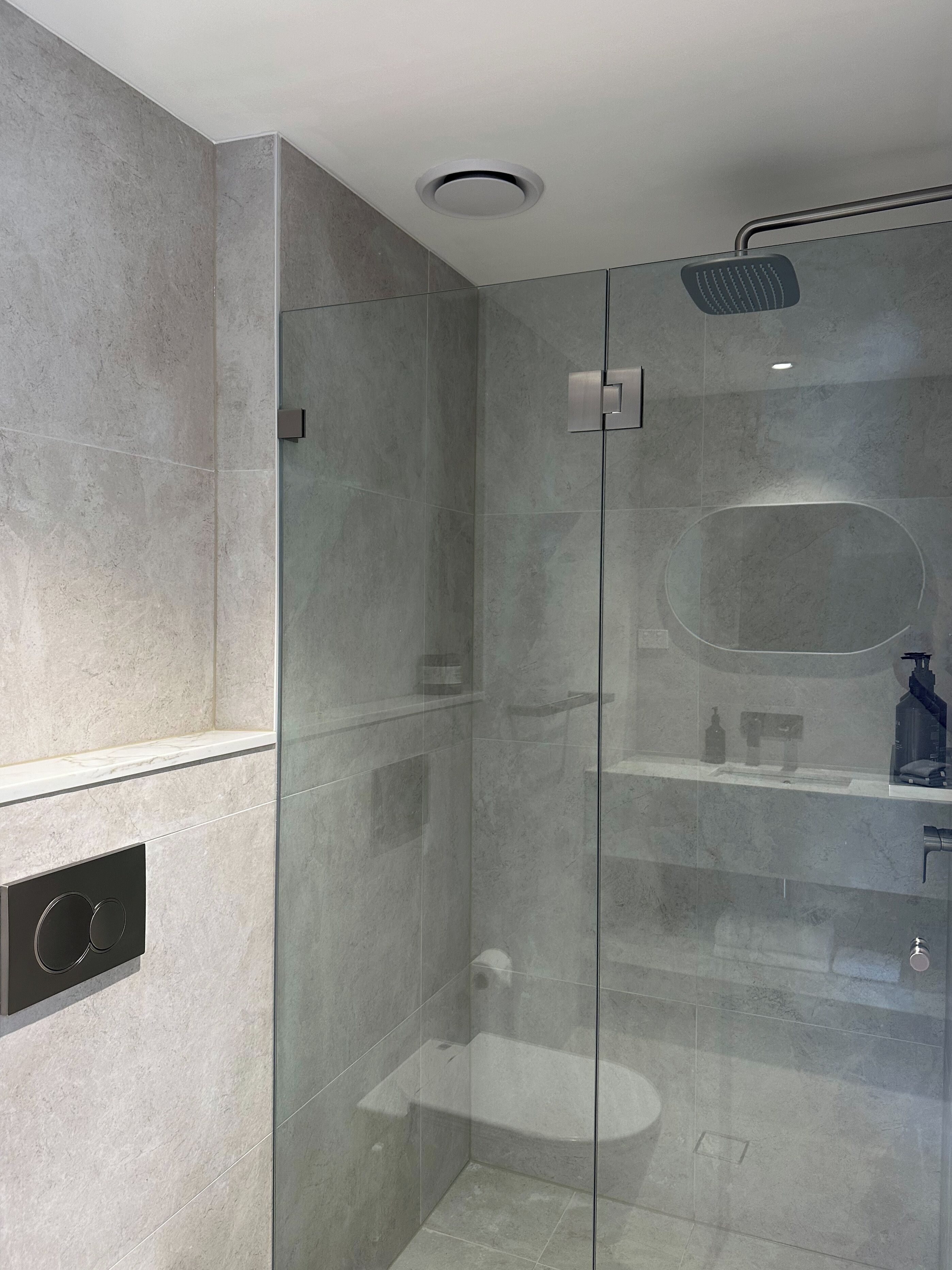 Un baño moderno con ducha acristalada, inodoro y lavamanos.