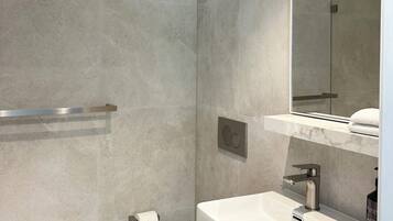 Ein modernes Badezimmer mit Toilette, Waschbecken und Duschbereich.