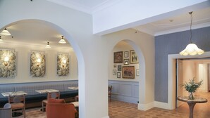 Vestíbulo de hotel con piso a cuadros, zonas de estar y obras de arte en la pared.