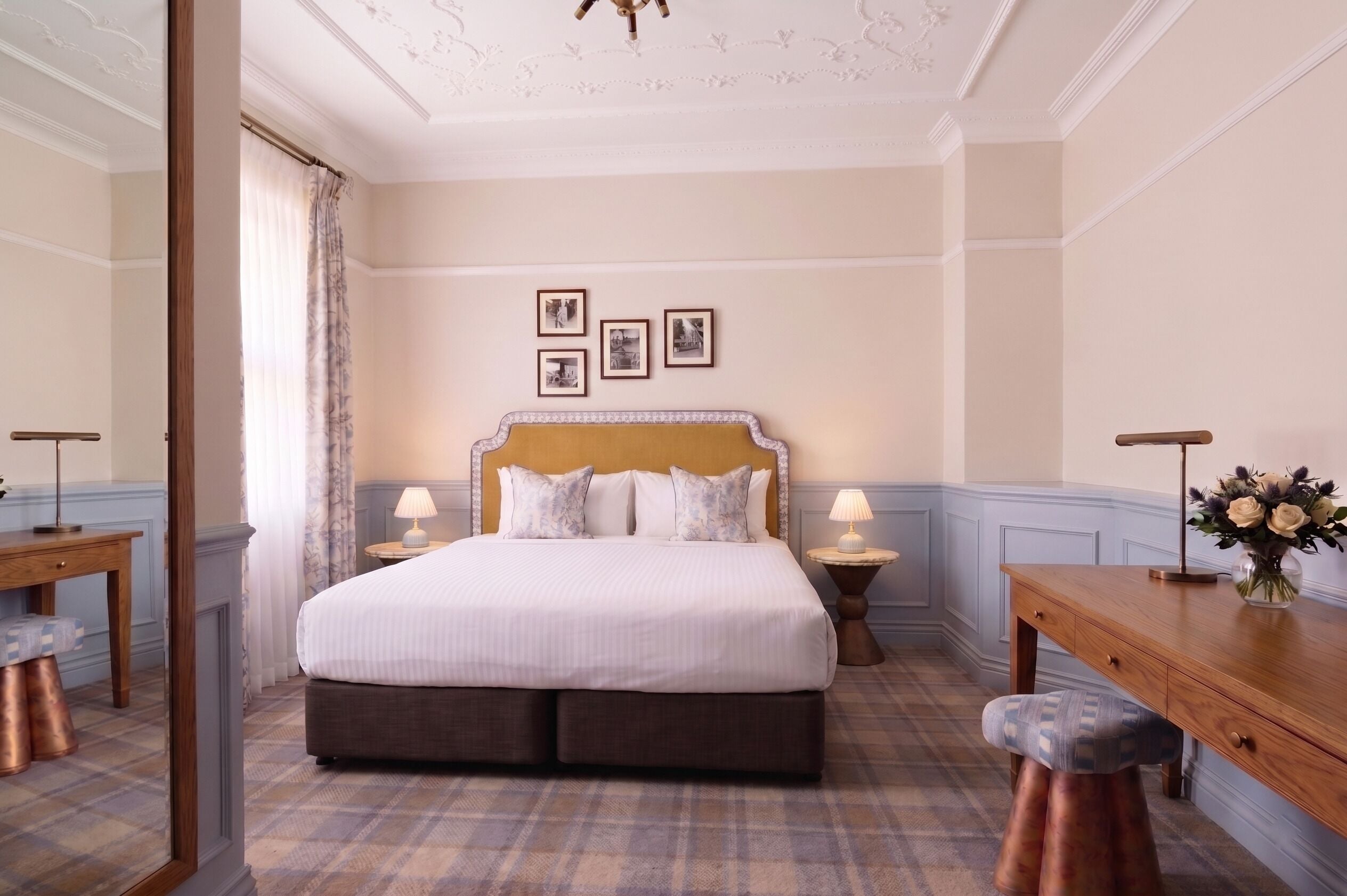 A hotel room with a large bed, two bedside tables with lamps, a small desk, and a mirror.