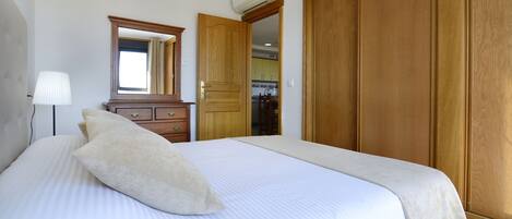 A bedroom with a large bed, a dresser, a mirror, and a wardrobe.