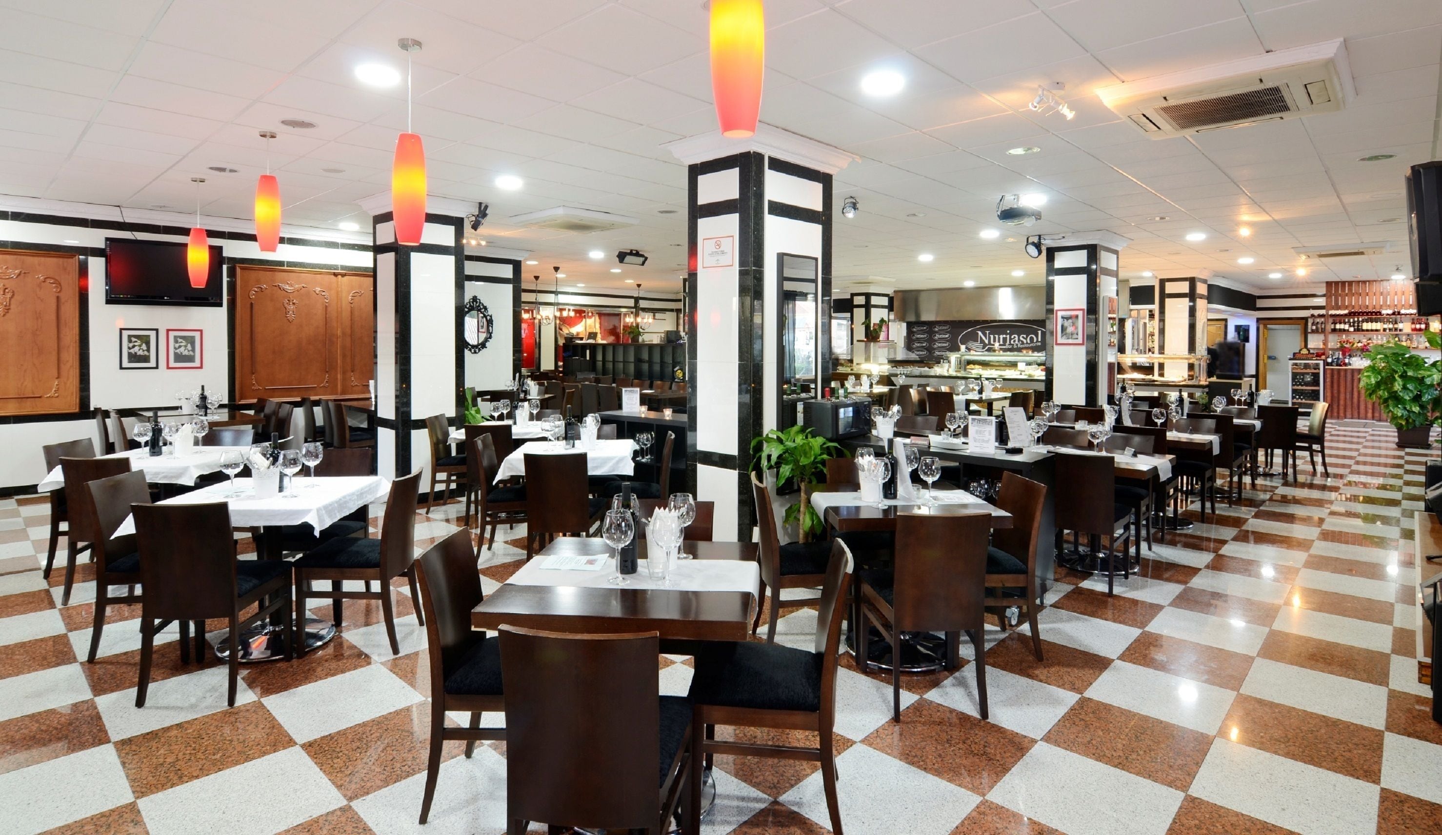 Un restaurante con piso a cuadros, varias mesas para comer y sillas.